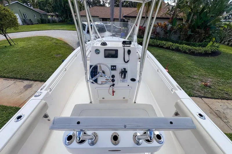 Slide: The Image of 2022 Cobia 220 Center Console boat with steering wheel and control panel, parked in driveway. - 25
