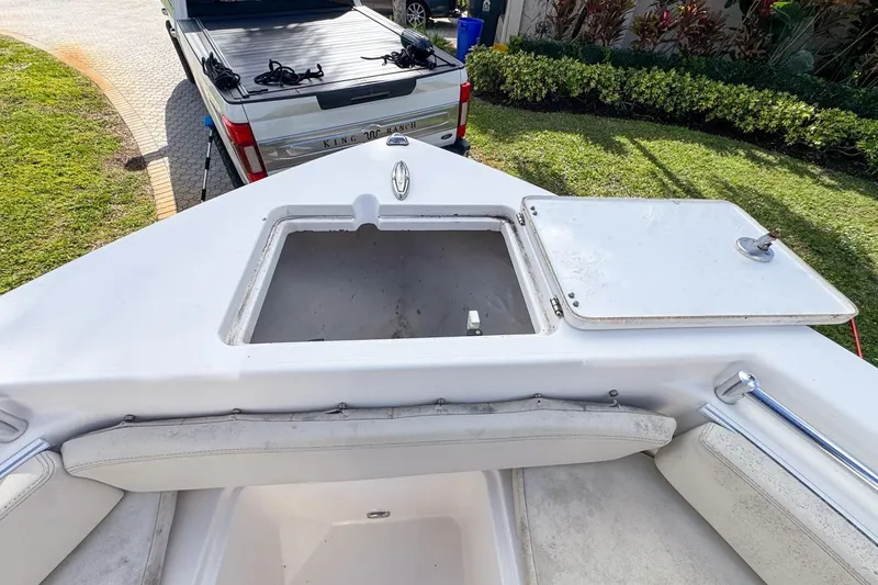 Slide: The Image of 2022 Cobia 220 Center Console boat with open storage compartment, parked near a pickup truck. - 46