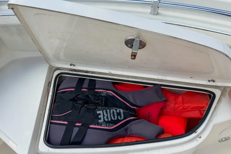 Slide: The Image of Open storage compartment on 2022 Cobia 220 Center Console with life jackets inside. - 48