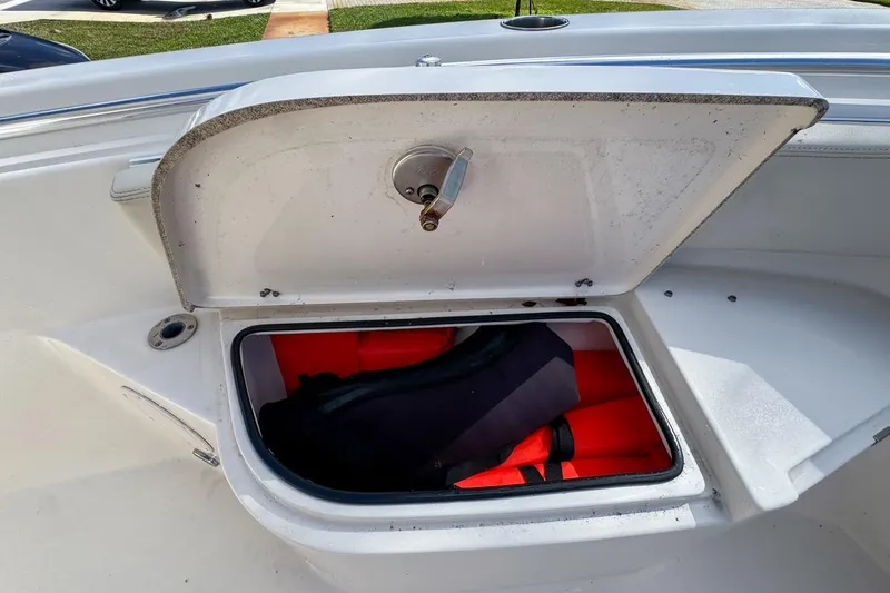 Slide: The Image of Open storage compartment on 2022 Cobia 220 Center Console boat with life jackets inside. - 49