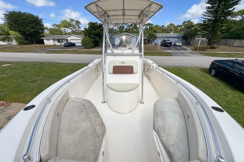 Slide: The Image of 2022 Cobia 220 Center Console boat with seating, parked in a residential area. - 52