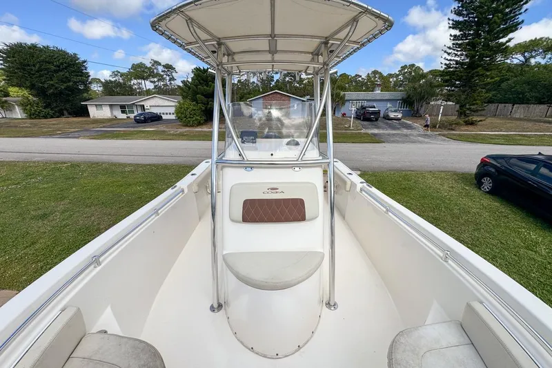 Slide: The Image of 2022 Cobia 220 Center Console boat with T-top, parked in a suburban neighborhood. - 55