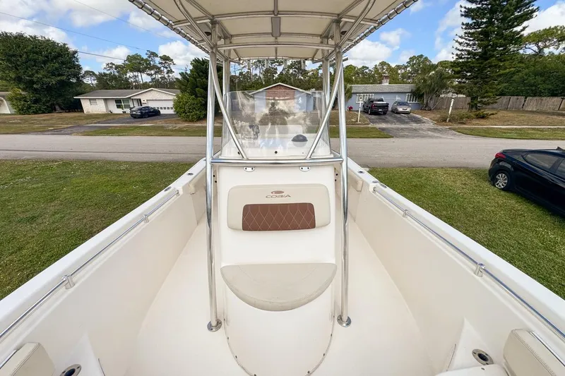 Slide: The Image of 2022 Cobia 220 Center Console boat with seating, parked in a residential area. - 59