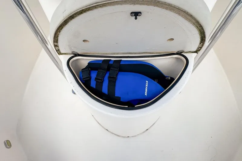 Slide: The Image of 2022 Cobia 220 Center Console storage compartment with blue life jacket inside. - 61