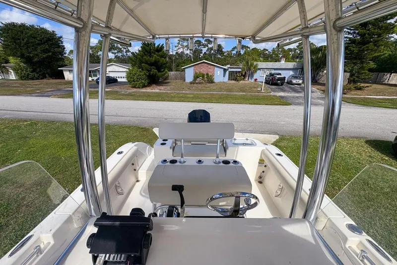 Slide: The Image of 2022 Cobia 220 Center Console boat interior with steering wheel and seating, parked in residential area. - 63