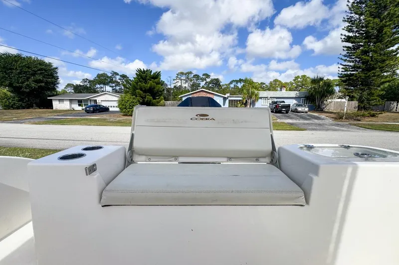 Slide: The Image of 2022 Cobia 220 Center Console boat seat with cup holders, parked in a suburban neighborhood. - 77