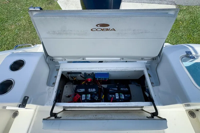 Slide: The Image of 2022 Cobia 220 Center Console boat battery compartment open, showing internal components. - 79