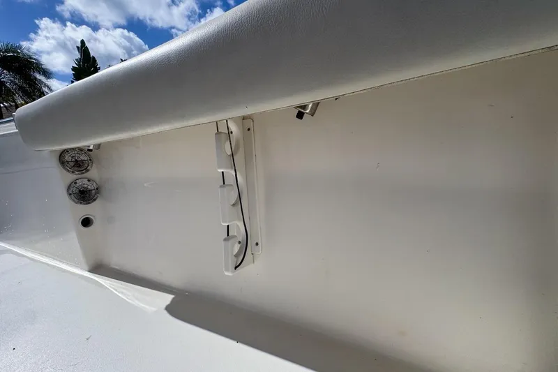 Slide: The Image of 2022 Cobia 220 Center Console boat interior with rod holders and seating under a blue sky. - 87