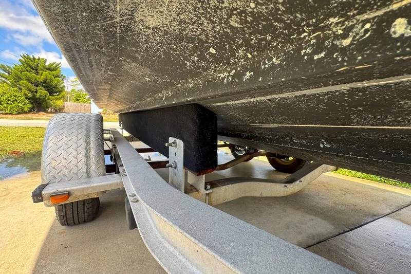 Slide: The Image of 2022 Cobia 220 Center Console boat on trailer, close-up view of hull and wheel. - 94