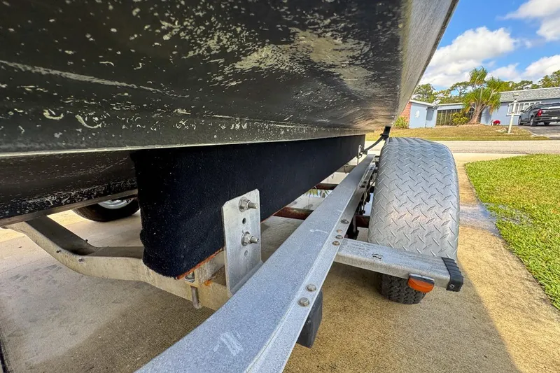 Slide: The Image of 2022 Cobia 220 Center Console boat on trailer, close-up view of hull and wheel. - 97