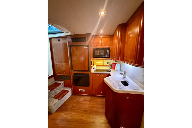 Slide: The Image of 2007 Cruisers Yachts 370 Express interior kitchen with wood cabinetry and modern appliances. - 11