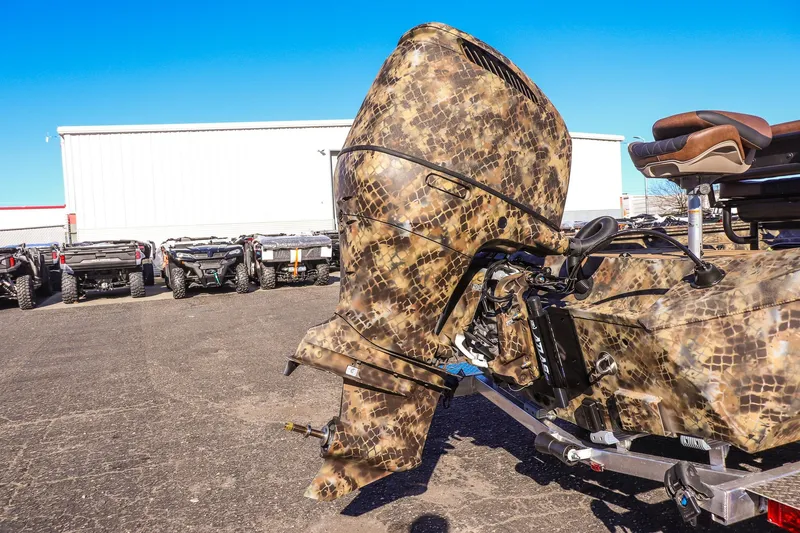 Slide: The Image of 2026 Excel 220 Bay Pro Elite boat with camouflage design, parked outdoors. - 21