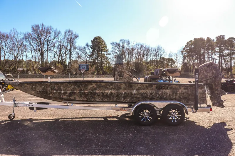 Slide: The Image of 2026 Excel 220 Bay Pro Elite boat on trailer, camo design, parked outdoors. - 5