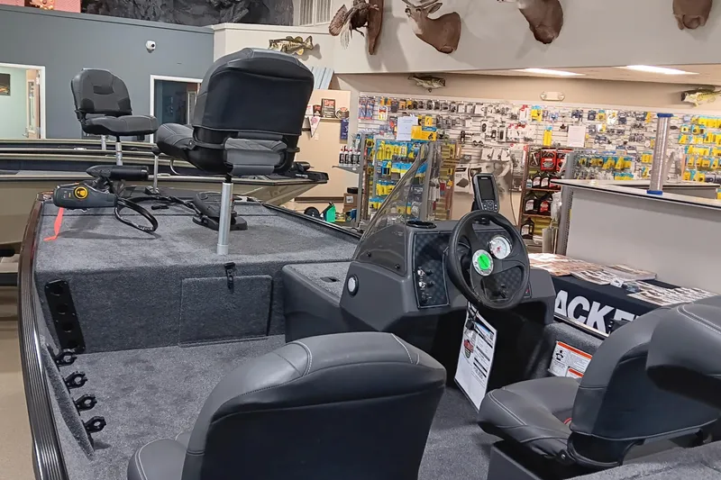 Slide: The Image of 2026 Tracker Bass Tracker Classic XL boat interior in showroom, featuring seating and control panel. - 11