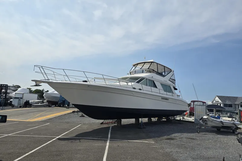 Slide: The Image of 1999 Sea Ray 550 Sedan Bridge yacht on dry dock under clear blue sky. - 3