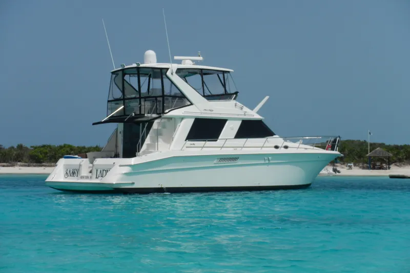 Slide: The Image of 1998 Sea Ray 550 Sedan Bridge yacht anchored in clear turquoise waters. - 64