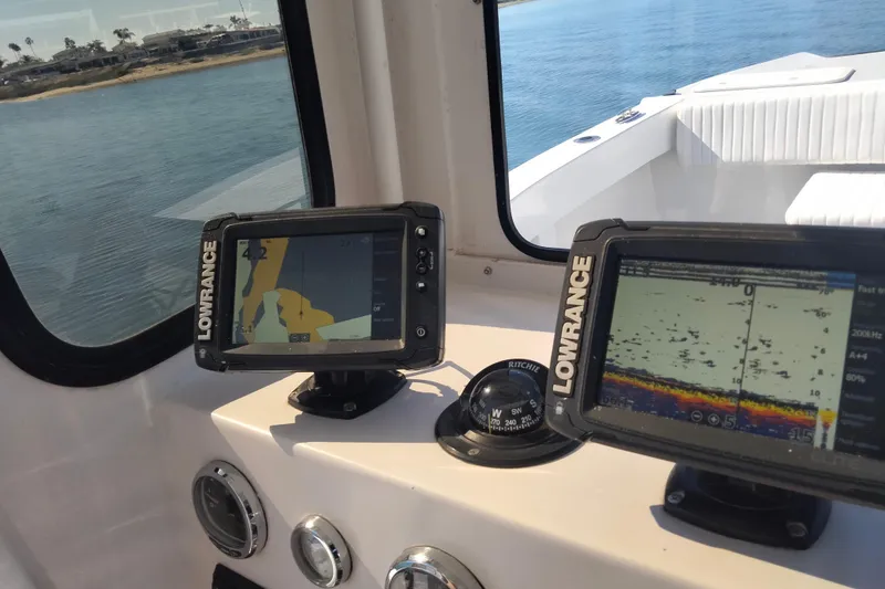 Slide: The Image of Pilot House Catamaran 2021 cockpit with Lowrance navigation displays and compass, near shoreline. - 16