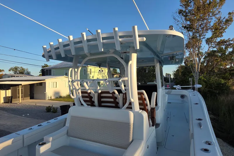 Slide: The Image of 2024 Costa Custom Boats 34 SV interior with seating and console, surrounded by lush greenery. - 9