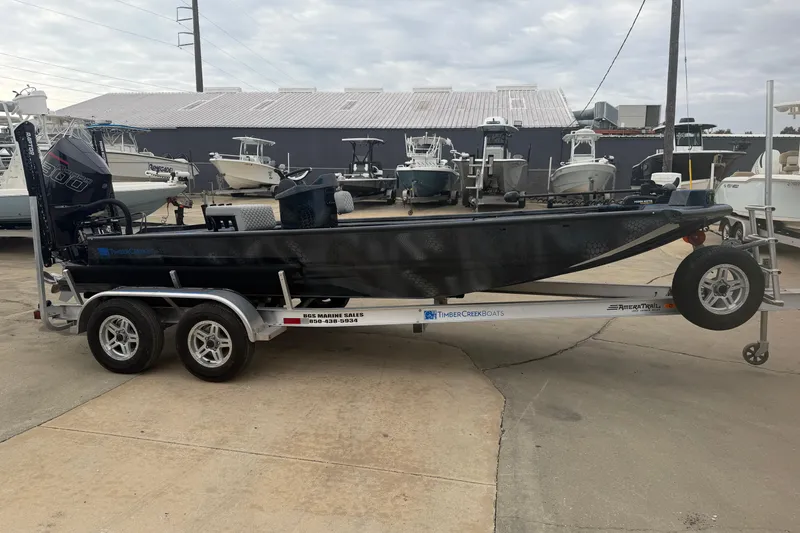 Slide: The Image of 2025 Timber Creek 2064 boat on trailer, parked in marina with other boats. - 2