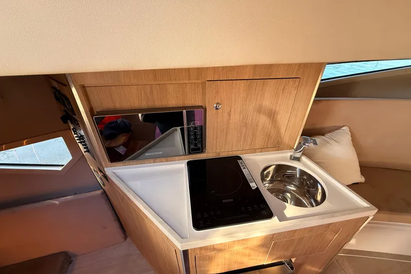 Slide: The Image of Compact kitchen area in 2023 NX Boats 360 Sport Coupe with sink and cooktop. - 11