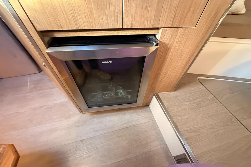 Slide: The Image of Compact fridge in 2023 NX Boats 360 Sport Coupe interior, featuring wood paneling. - 14