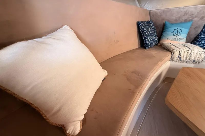 Slide: The Image of Interior of 2023 NX Boats 360 Sport Coupe with cozy seating and decorative pillows. - 16