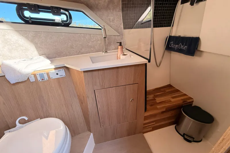 Slide: The Image of 2023 NX Boats 360 Sport Coupe bathroom with modern sink, toilet, and wooden accents. - 27