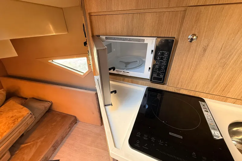 Slide: The Image of 2023 NX Boats 360 Sport Coupe interior kitchen with microwave and induction cooktop. - 30