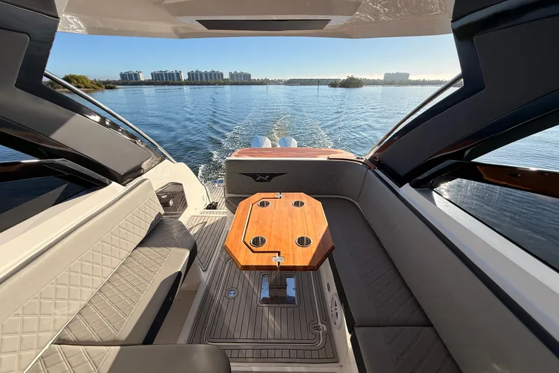 Slide: The Image of 2023 NX Boats 360 Sport Coupe interior with elegant seating and wooden table on open water. - 37