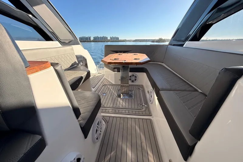 Slide: The Image of 2023 NX Boats 360 Sport Coupe interior with sleek seating and table, overlooking water. - 39