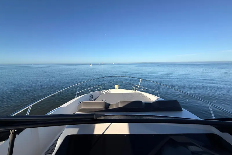 Slide: The Image of 2023 NX Boats 360 Sport Coupe cruising on calm ocean waters under clear blue sky. - 45