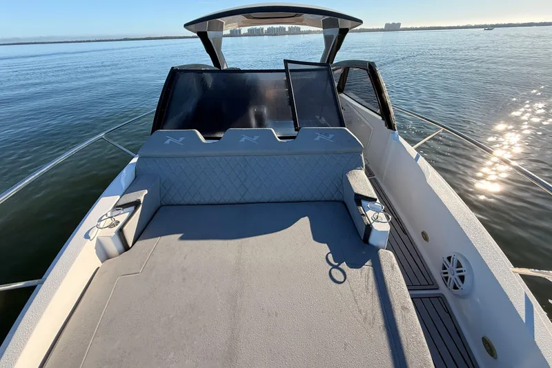 Slide: The Image of 2023 NX Boats 360 Sport Coupe on calm water, showcasing spacious deck and sleek design. - 54