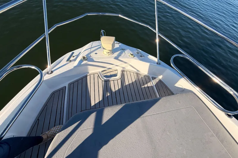 Slide: The Image of Bow of 2023 NX Boats 360 Sport Coupe on calm water, featuring sleek deck design. - 58