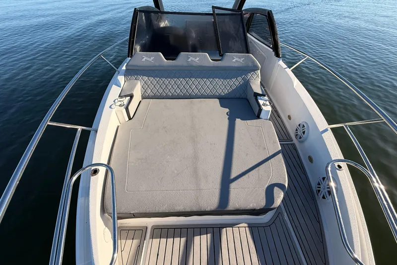 Slide: The Image of 2023 NX Boats 360 Sport Coupe deck with cushioned seating, surrounded by calm water. - 60