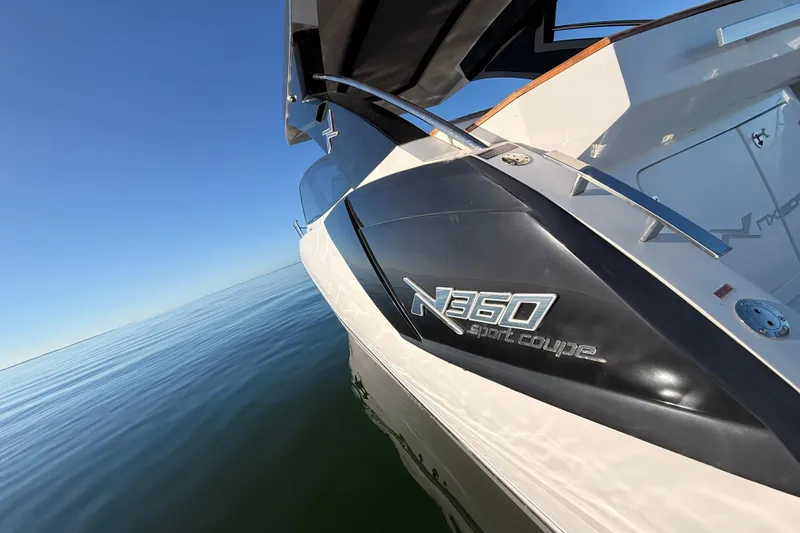 Slide: The Image of 2023 NX Boats 360 Sport Coupe on calm water under clear blue sky. - 65