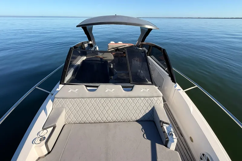 Slide: The Image of 2023 NX Boats 360 Sport Coupe on calm water, showcasing sleek design and luxury seating. - 69