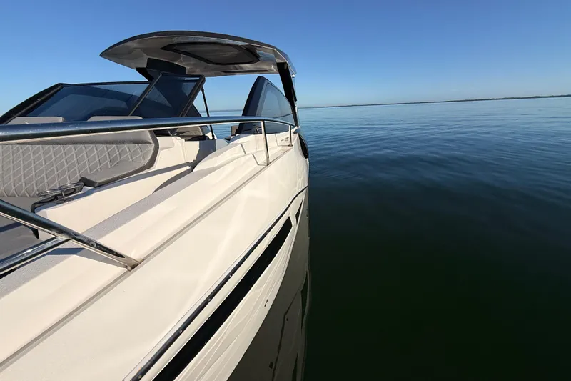 Slide: The Image of 2023 NX Boats 360 Sport Coupe cruising on calm waters under clear blue sky. - 73
