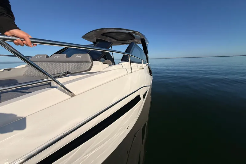 Slide: The Image of 2023 NX Boats 360 Sport Coupe cruising on calm waters under clear blue sky. - 74