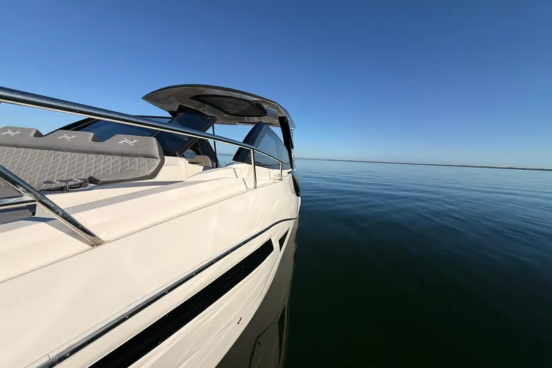 Slide: The Image of 2023 NX Boats 360 Sport Coupe cruising on calm waters under clear blue sky. - 75