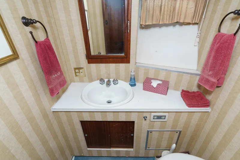 Slide: The Image of 1971 Hatteras 53 Motor Yacht bathroom with sink, mirror, and red towels. - 42