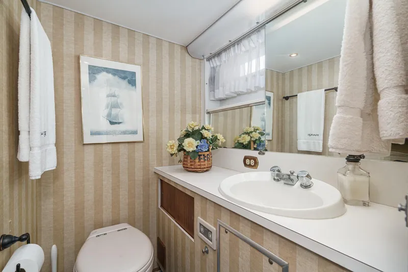 Slide: The Image of 1971 Hatteras 53 Motor Yacht bathroom with striped wallpaper, floral decor, and nautical artwork. - 49