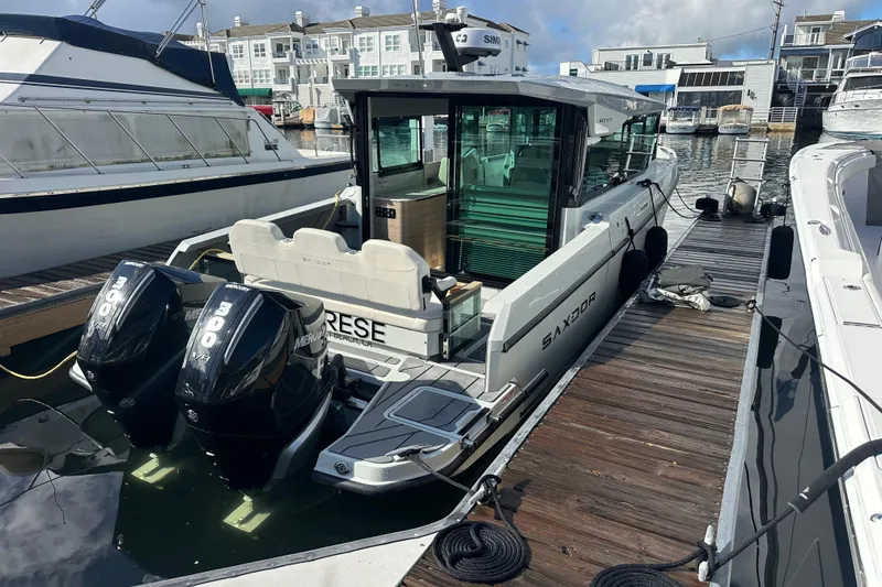 Slide: The Image of 2024 Saxdor 320 GTC boat docked with dual Mercury engines, marina background. - 75