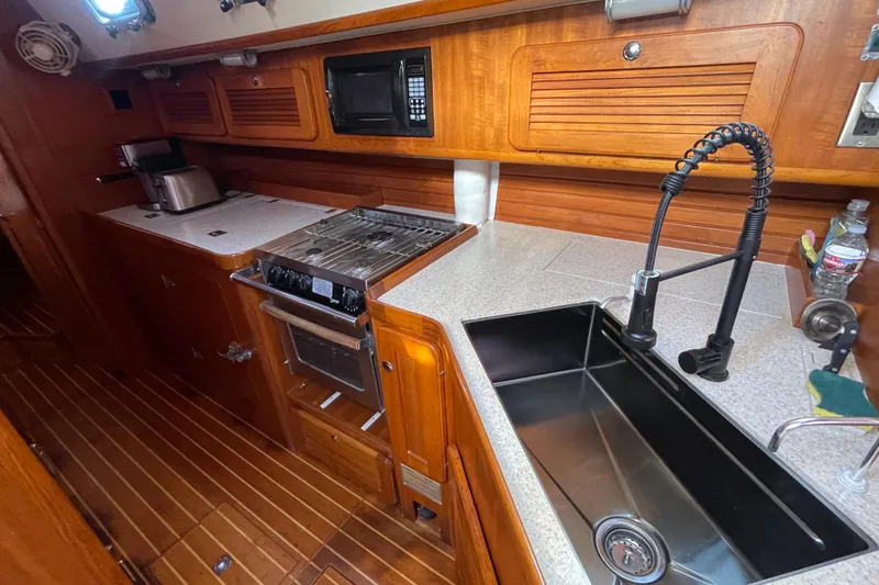 Slide: The Image of 2008 Caliber center cockpit cutter interior with wood finish, dining area, and kitchen amenities. - 38