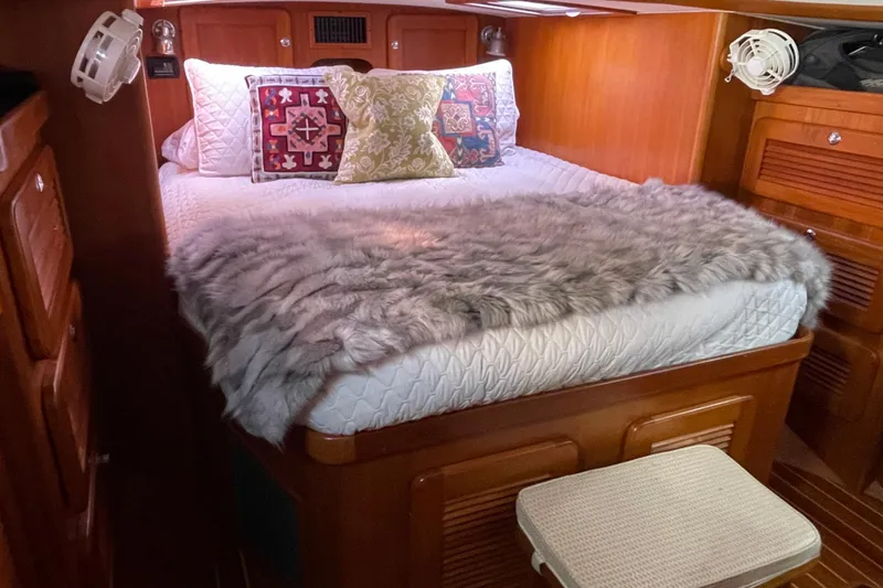 Slide: The Image of 2008 Caliber center cockpit cutter interior with open fridge, wooden cabinetry, and cozy sleeping area. - 45