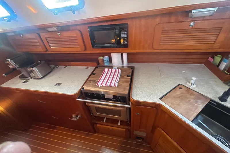 Slide: The Image of Kitchen area of 2008 Caliber 47 LRC yacht with wooden cabinetry and modern appliances. - 73