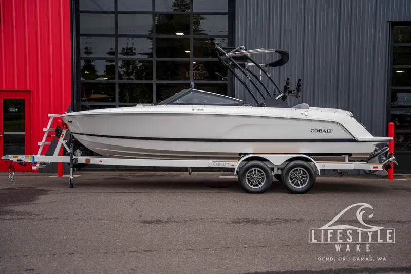 The Image of 2026 Cobalt CS22 boat on trailer, parked outside a modern building. - 0
