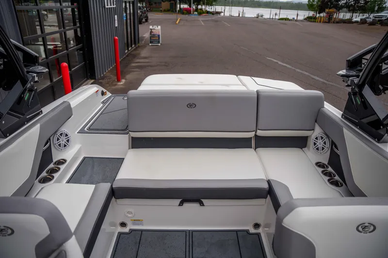 Slide: The Image of 2026 Cobalt CS22 boat interior with gray seating and cup holders, parked near a waterfront. - 16