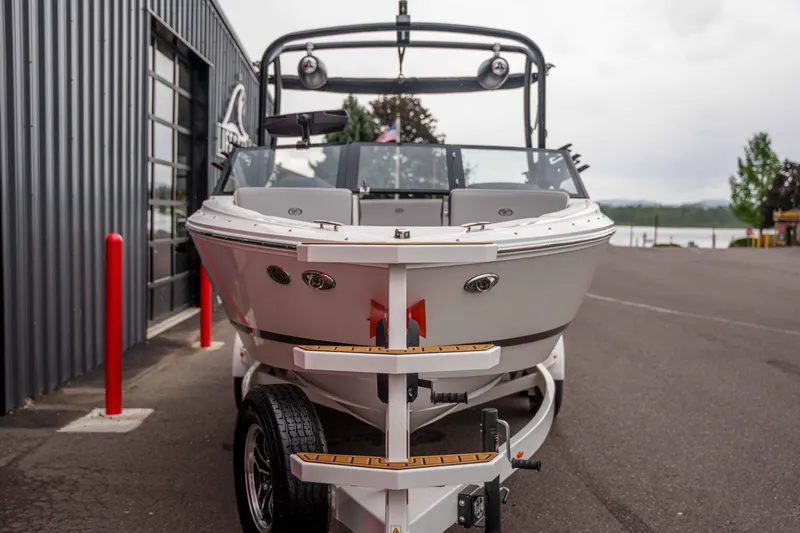 Slide: The Image of 2026 Cobalt CS22 boat on trailer, parked near a modern building. - 2