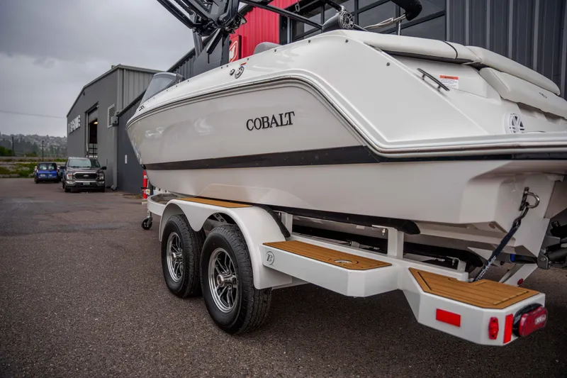 Slide: The Image of 2026 Cobalt CS22 boat on trailer, parked outside a building on a cloudy day. - 23