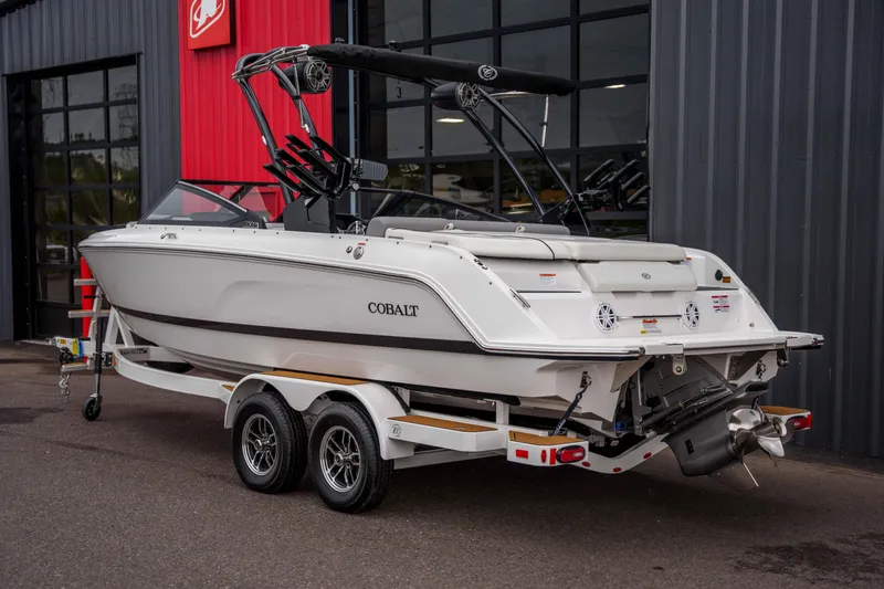 Slide: The Image of 2026 Cobalt CS22 boat on trailer, parked outside a building with red and gray walls. - 3